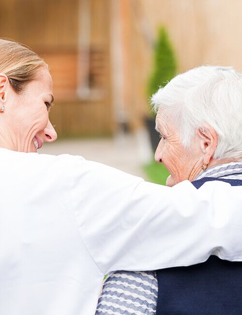Caregiver supporting an older woman after a hospital stay